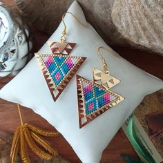 a pair of earrings sitting on top of a white pillow next to some other items