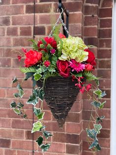 a hanging basket filled with red and green flowers next to a brick wall in front of a door