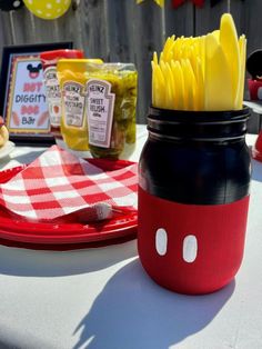 a mickey mouse mason jar with fries in it on a red and white checkered table cloth