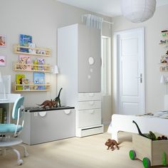 a child's bedroom decorated in white and blue with toy dinosaurs on the floor