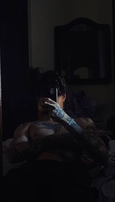 a man with tattoos on his arm is taking a selfie in the dark room