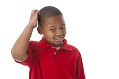 a young boy in a red polo shirt holding his hair up to the side with one hand