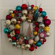 a christmas wreath with ornaments hanging on the front door to hang from it's side