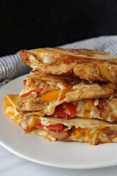 three quesadillas stacked on top of each other with cheese and tomato toppings