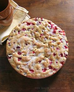 a cookie with crumbs and powdered sugar sitting on a table next to a cup of coffee