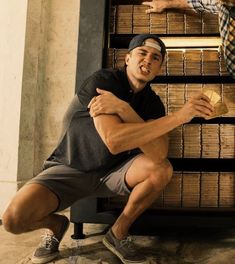 a man kneeling down next to a book shelf