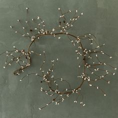 a wreath made out of branches and white flowers on a gray background with the word love written below it