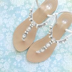 a pair of white sandals with pearls on the toes and toe are sitting on a blue floral background