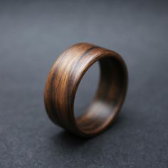 a wooden ring sitting on top of a black table next to a gray wall and floor