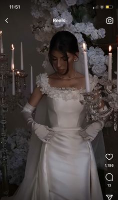 a woman in a wedding dress holding a candle and looking down at her phone screen