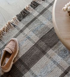 a pair of brown shoes sitting on top of a rug next to a wooden table