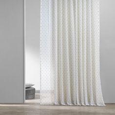 a white curtain with polka dots on it in front of a door and window sill