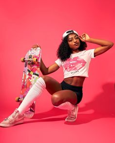 a woman kneeling on the ground holding a skateboard