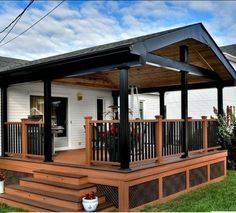 a small white house with a black roof and wooden steps leading to the front door