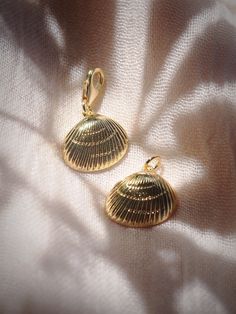 two gold earrings sitting on top of a white cloth