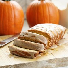 sliced loaf of bread sitting on top of a cutting board next to two pumpkins