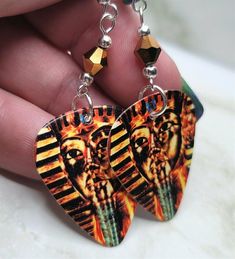 a pair of earrings with an image of two egyptian pharaohs on the front and back of them