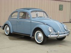 an old blue car parked in front of a building