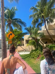 two women walking down a sidewalk next to palm trees