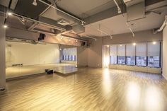 an empty room with hard wood floors and large windows in the center is lit by spotlights