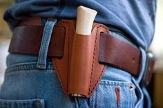 a person wearing jeans and holding a brown leather belt with a wooden stick sticking out of it