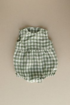 Product photos - green gingham. The model is wearing a romper in yellow gingham. All-day comfort is guaranteed with this sleeveless romper crafted from gingham linen. The fabric is soft, breathable, and light on the skin. For simple changing, the romper is designed with popper snap fastenings on the shoulders and bottom. The waist seam in the middle adds a nice final touch to an adorable silhouette, and elasticated leg cuffs secure the romper in place. This baby romper is designed to be comfortably loose-fitting and allow for growth as the baby grows. Summer Cotton Green Jumpsuits And Rompers, Cute Green Cotton Jumpsuits And Rompers, Cute Gingham Bubble Romper For Spring, Cute Spring Gingham Bubble Romper, Cute Gingham Cotton Bubble Romper, Cute Cotton Gingham Bubble Romper, Cute Gingham Bubble Romper, Green Casual Bubble Romper For Summer, Casual Green Bubble Romper For Spring