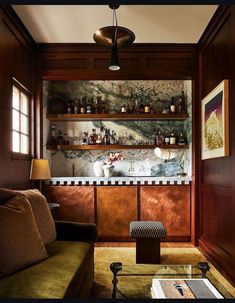 a living room filled with furniture and lots of bottles on the shelves above it's bar