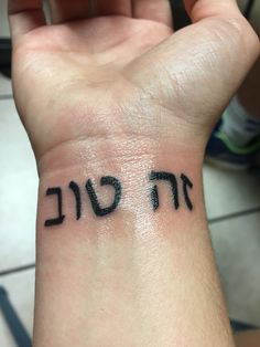 a person with a wrist tattoo that has the word hebrew written in black on it