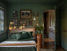 a bedroom with green walls and pictures on the wall above the bed, along with a wooden headboard