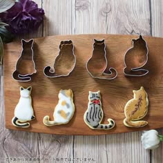 the cookie cutters are shaped to look like cats on a wooden board with flowers in the background