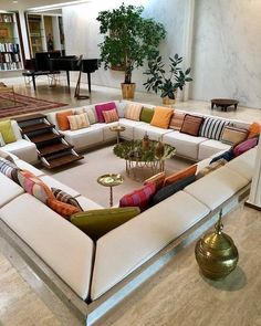 a large sectional couch with many pillows on it in a living room next to a piano