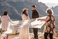 a group of people standing on top of a mountain next to each other holding a white scarf