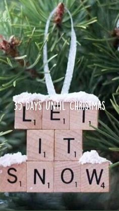 a wooden block ornament with the words let it snow hanging from a pine tree