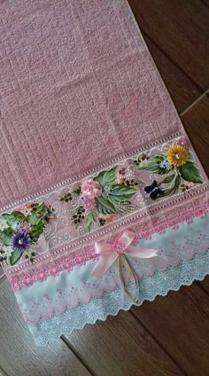 a pink table cloth with flowers and lace on it, sitting on a wooden floor