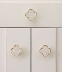 two white cupboards with gold handles and knobs on the doors, one has a flower design