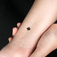 two hands holding each other with a small leaf tattoo on the left side of their wrist