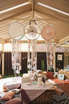 an outdoor area with lots of pillows and decorations hanging from the ceiling, including fan shaped chandeliers