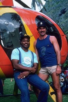 two men sitting in front of a helicopter