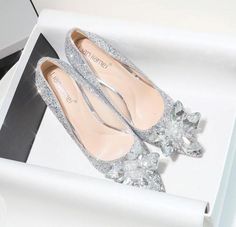 a pair of silver shoes sitting on top of a white box