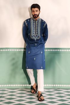 Teal blue kurta with geometric embroidered placket in cutdana, beads and mirror work. Paired with a pant.
Components: 2
Pattern: Embroidery
Type Of Work: Geometric, Beads, Cutdana
Neckline: Stand Collar
Sleeve Type: Full Sleeves
Fabric: Padma Silk
Color: Blue
Other Details: 
Embroidered buttis on kurta
Arm-hole embroidery in cutdana and beads
Note: The red kurta set worn by the other model is not for sale
Occasion: Sangeet - Aza Fashions Kurta With Hand Embroidery, Men Embroidery Kurta Design, Sky Blue Kurta Men, Mens Sangeet Outfit, Sangeet Outfit For Men, Designer Kurta For Men, Traditional Indian Mens Clothing, Hole Embroidery, Kurta Designs Men's