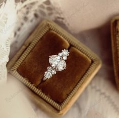 an engagement ring sitting on top of a velvet box