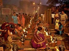 many people are standing around with candles in their hands and on the ground while others stand near them