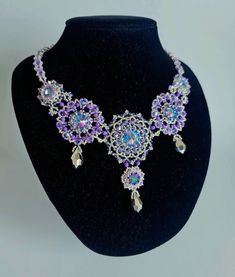 a purple and blue necklace on a black mannequin with jewels in the center