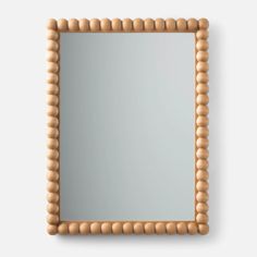 a wooden frame mirror with beaded edges on a white wall, viewed from above