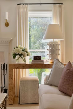 a living room filled with furniture and a lamp on top of a wooden table in front of a window