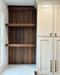 an empty kitchen with wooden shelves and white counter tops in front of the cupboards