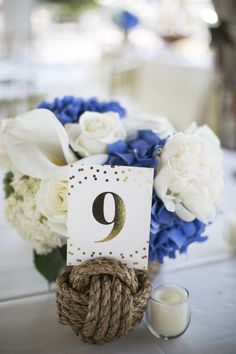 a table topped with a vase filled with white and blue flowers next to a candle