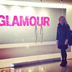 a woman standing in front of a glass door with the word glamour written on it