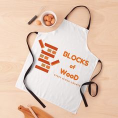 a white apron with the words blocks of wood on it next to wooden utensils