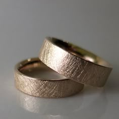 two gold wedding bands sitting on top of each other